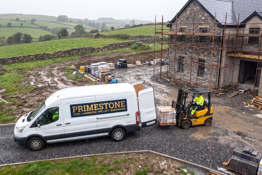 Primestone delivery van and forklift unloading materials at a countryside house under construction
